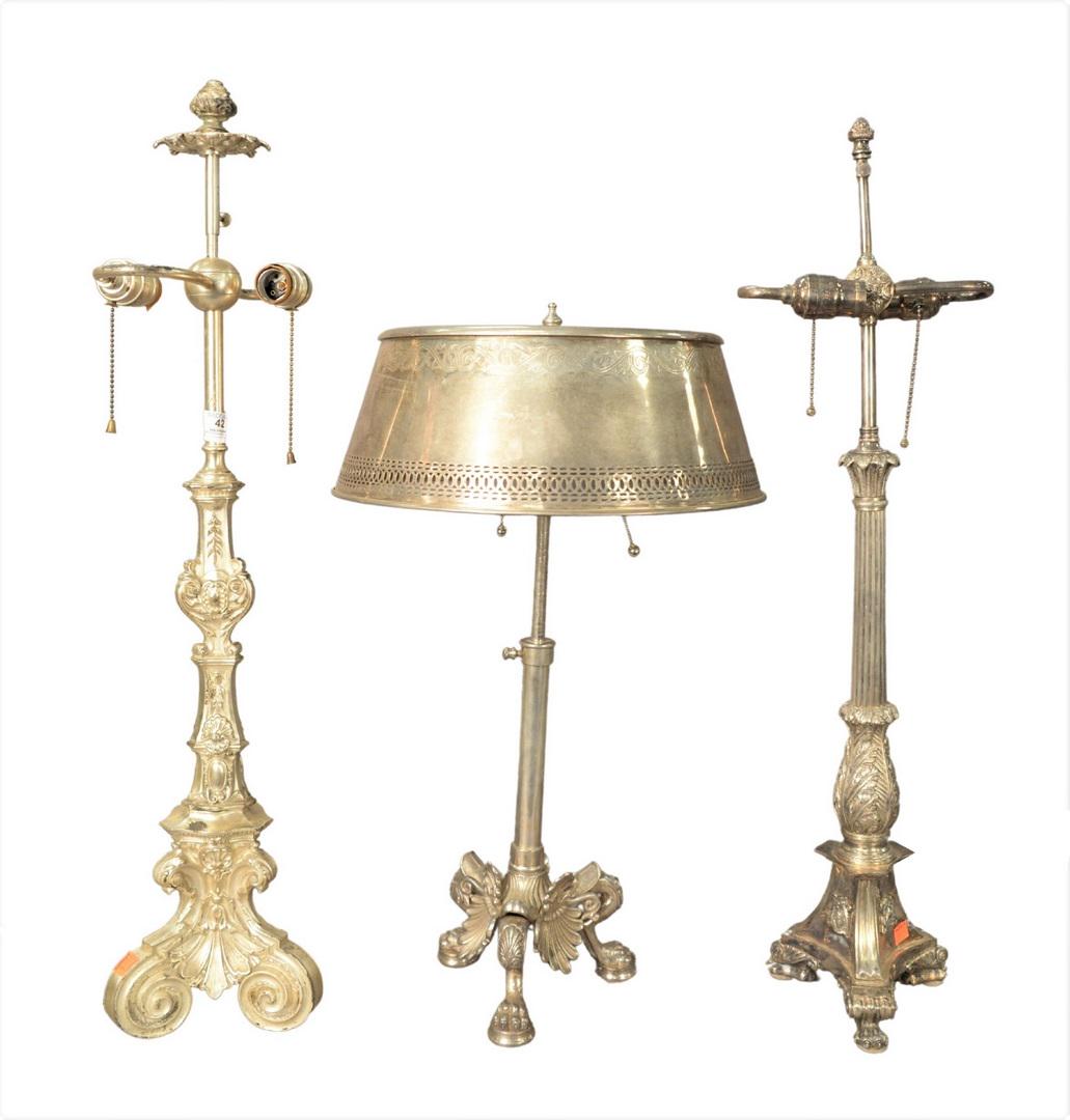 Group of Three Silvered Table Lamps, to include two: Group of Three Silvered Table Lamps, to include two candlestick form raised on paw feet, along with an adjustable bouillotte lamp; height 31 inches.