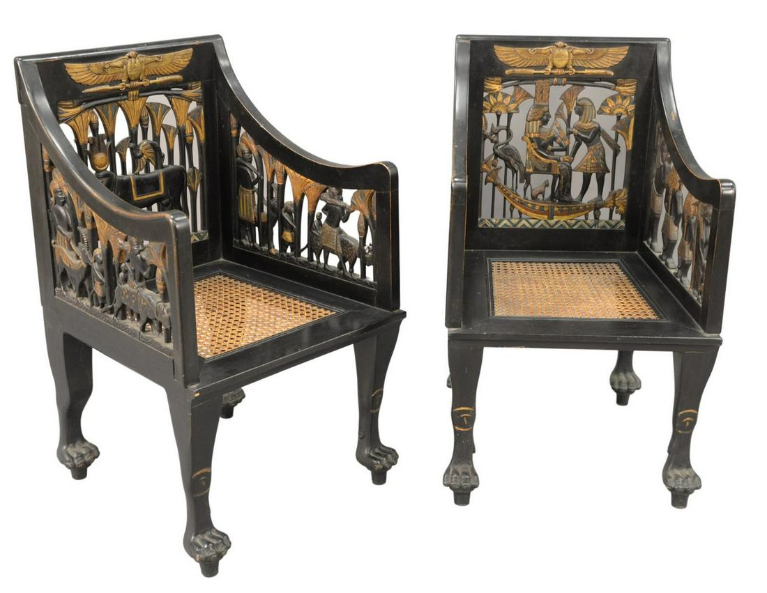 Pair of Egyptian Revival Ebonized Armchairs, having: Pair of Egyptian Revival Ebonized Armchairs, having pierced carved backs, arm supports, and caned seats on paw feet, height 37 inches, width 23 inches, depth 23 inches.