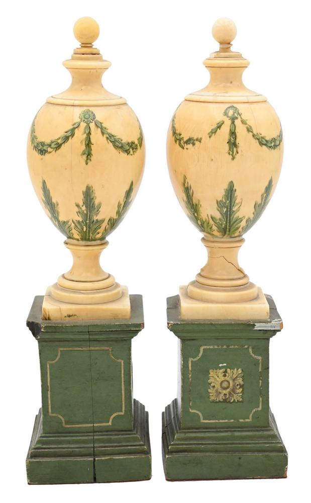 Pair of Painted Urns, each in egg form with finial, painted with garland and foliage, on a green: Pair of Painted Urns, each in egg form with finial, painted with garland and foliage, on a green painted pedestal base, height 9 inches. This item cannot be purchased or shipped by bidders residing ou