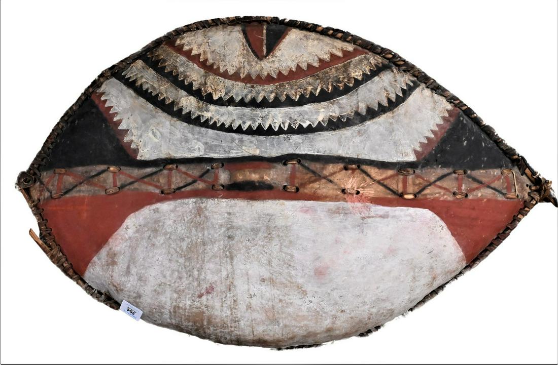 African Painted Leather Shield: African Painted Leather Shield, elliptical painted with red, white and black decoration with wood handle on back, 23" x 36". Provenance: Estate of Peter Tillou, Litchfield, Connecticut.