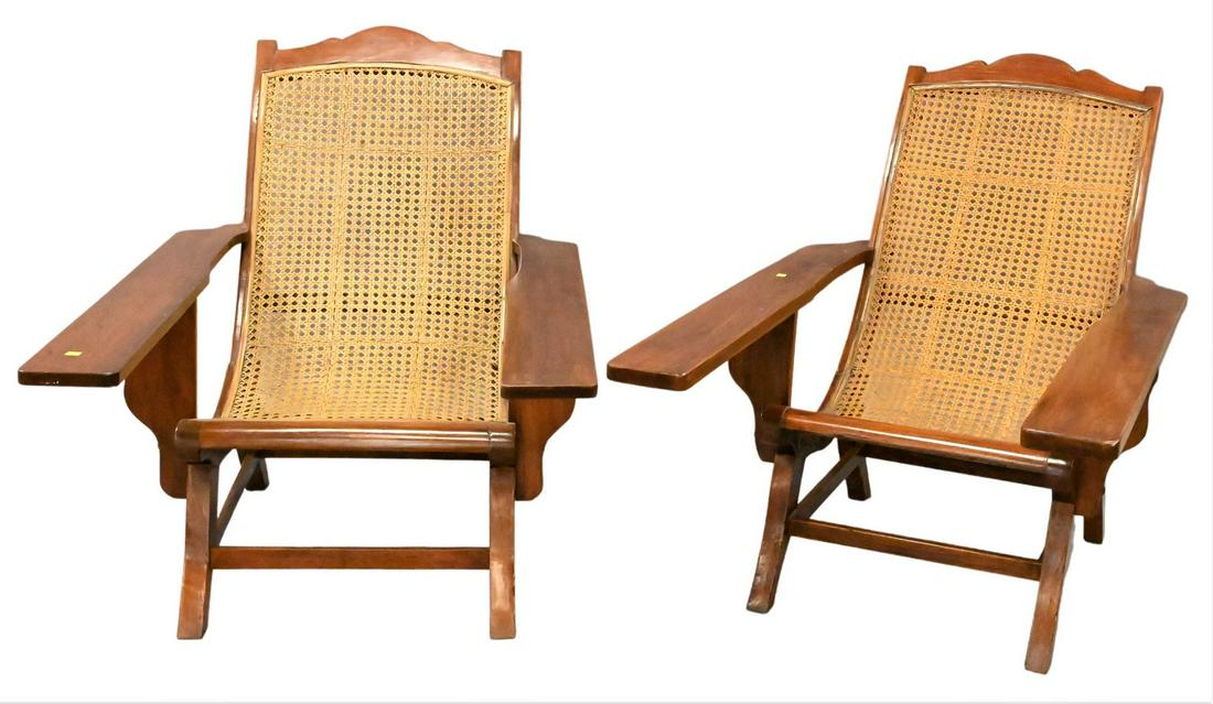 Pair of Plantation Chairs: Pair of Plantation Chairs, each having caned seats, backs and extended arms, height 38 inches, width 32 inches, depth 54 inches.