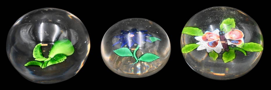 Three Baccarat Glass Paperweights: Three Baccarat Glass Paperweights to include a butterfly/moth surmounting a white flower having green foliage, cut star on bottom, diameter 3 inches; a small paperweight having blue flower, diameter 2