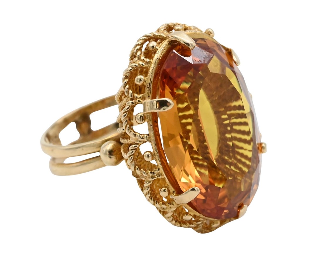 18K Yellow Gold Ring with Large Oval Citrine: 18K Yellow Gold Ring with Large Oval Citrine Decorative filigree setting centering an oval faceted citrine measuring 18.2mm x 27.4mm. Marked 18K. Size 8. Total weight 15.4g.