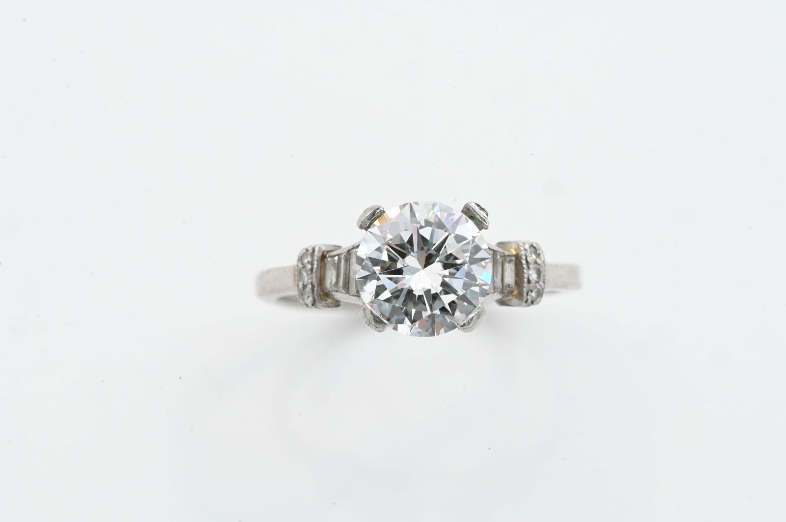 Vintage Platinum Ring with 2.11 ct Center Diamond: Vintage Platinum Ring with 2.11 ct Center Diamond A vintage platinum engagement ring set with a 2.11-carat round center diamond, in E color VS1, flanked by tapered baguette diamonds and additional sma