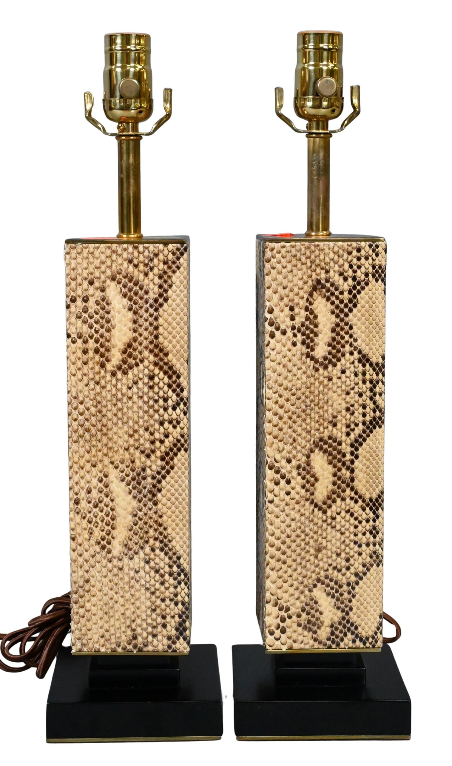 Pair of Mid Century Python Table Lamps: Pair of Mid Century Python Table Lamps of square column form with brass mounts over black lacquered base, woven chords height 19 inches Provenance: Property from a Private Collection Designed by Cullm