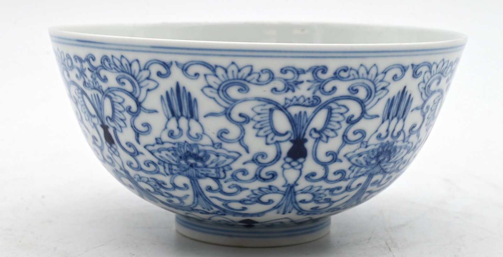Chinese Blue and White Porcelain Floral Bowl: Chinese Blue and White Porcelain Floral Bowl of rounded form, finely painted in underglaze blue featuring lotus blossoms in scrolling foliate decoration issuing leafy tendrils, above a band of ruyi la