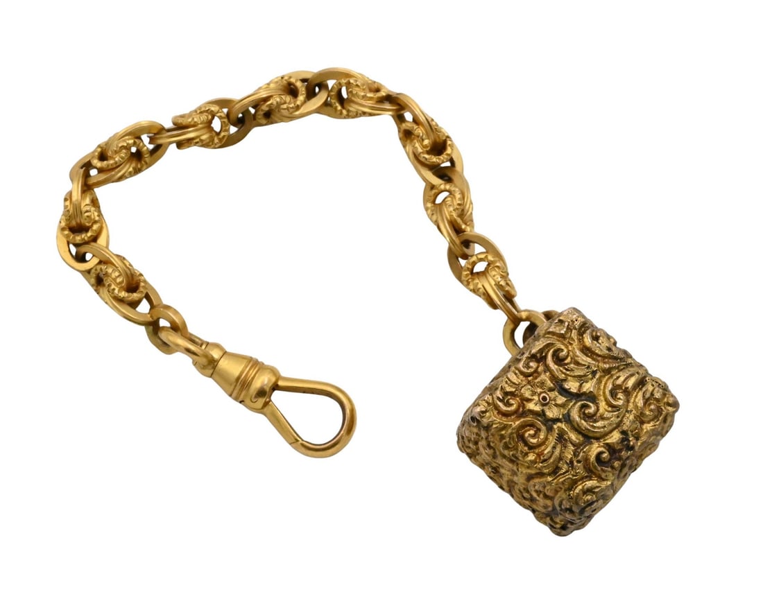 14K Yellow Gold Ornate Fob Chain with Textured Cube Pendant: 14K Yellow Gold Ornate Fob Chain with Textured Cube Pendant comprising an intricately linked 14K yellow gold chain suspending a chased and embossed cube-form pendant with scroll decoration; marked 14K