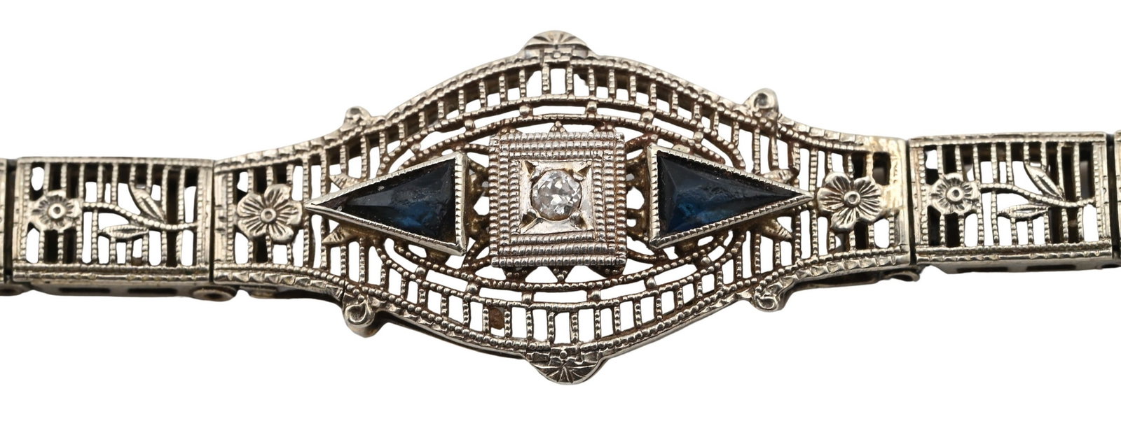 10k White Gold, Diamond, and Blue Sapphire Bracelet: 10k White Gold, Diamond, and Blue Sapphire Bracelet having pierced geometric links centered by a rectangular panel set with a small diamond, flanked by triangular blue sapphire accents in an Art Deco 