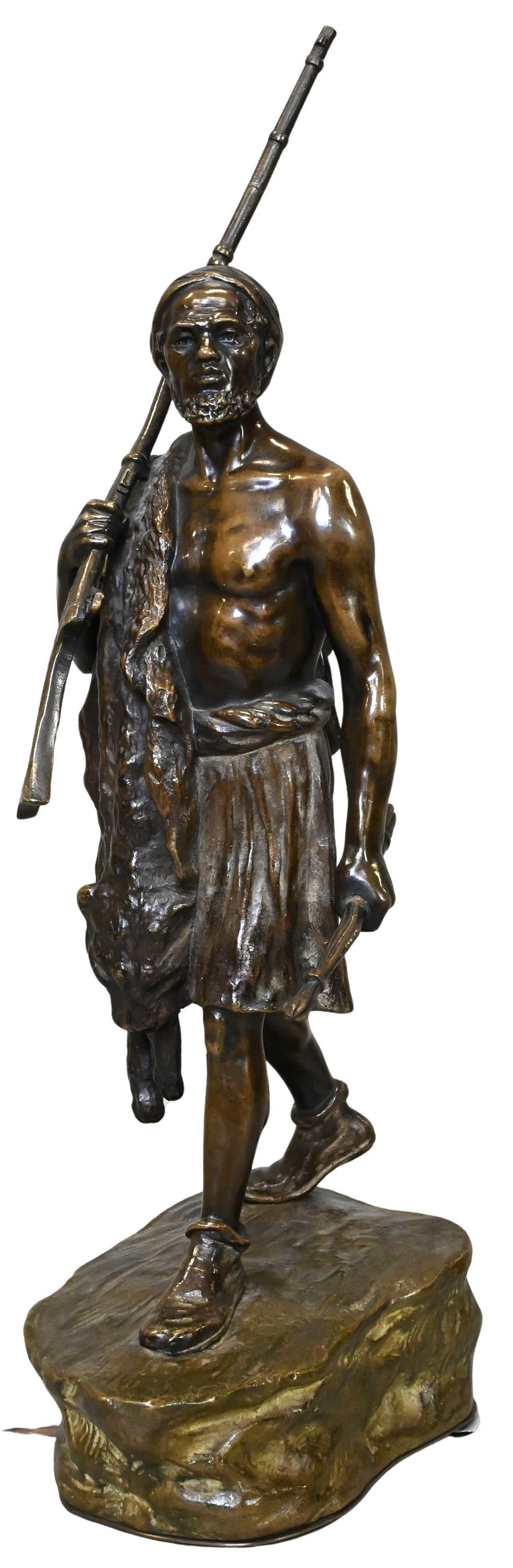 Andor Ruff (Hungarian 1885 - 1951): Andor Ruff (Hungarian 1885 - 1951) Figure of a Moorish Hunter with Lion Skin Patinated bronze, depicted standing and holding a rifle and implement, draped in a lion skin and dressed in exoticized