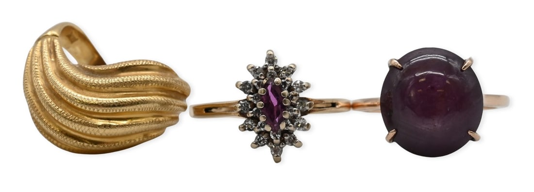 Three Yellow Gold Rings: Three Yellow Gold Rings to include one 18K gold ribbon form (size 5), along with two 14K gold, one with purple cabochon cut stone ( size 8), and one with marquise cut center stone with a halo of white