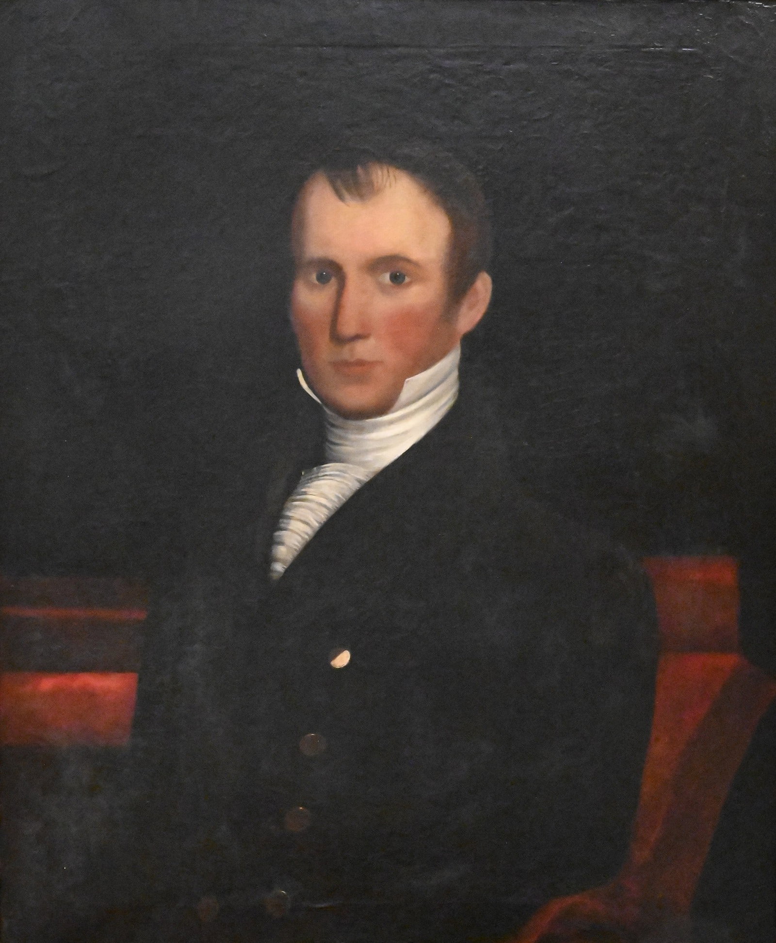American Primitive School (19th Century): American Primitive School (19th Century) Federal Portrait Of A Gentleman, circa 1830 oil on canvas, depicting a seated gentleman wearing a black coat and white cravat against a dark ground, housed in