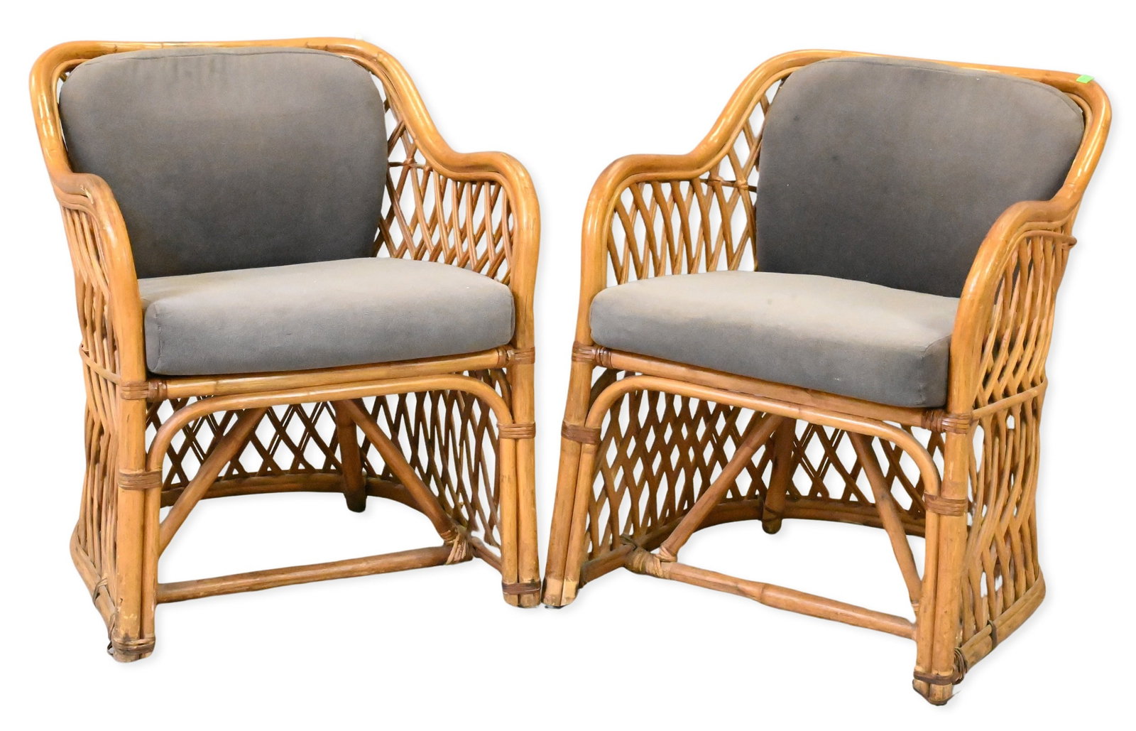 Pair of Mid-Century Style Rattan Lounge Chairs: Pair of Mid-Century Style Rattan Lounge Chairs each having a woven openwork frame, scrolling arms and loose upholstered seat and back cushions. Height 30 inches, width 24 inches, depth 25 inches