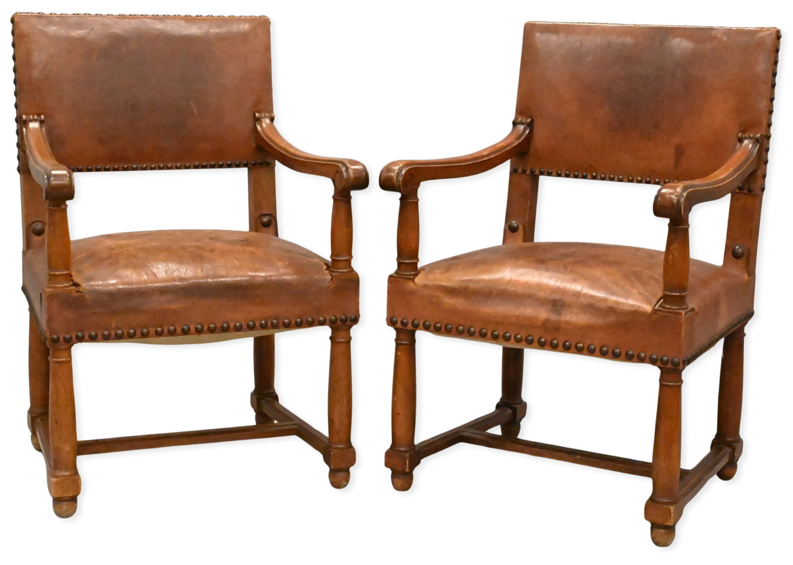 Pair of Spanish Style Leather Arm Chairs: Pair of Spanish Style Leather Armchairs having large brass nailhead trim, shaped wood arms, turned legs and stretcher base probably late 19th Century height 37 inches, width 24 inches