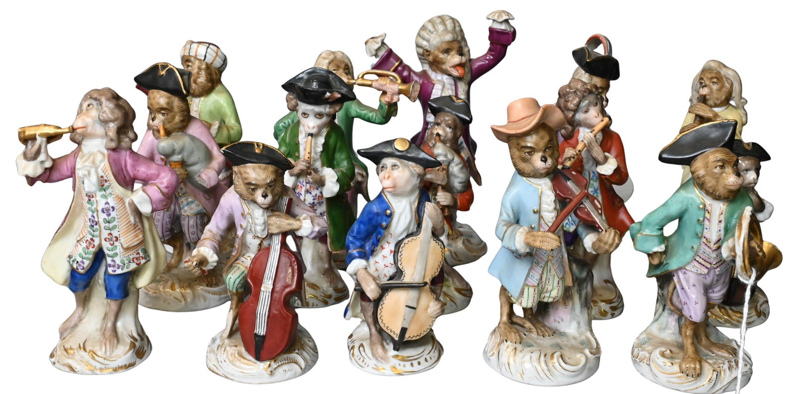 Fifteen Meissen Style Monkey Band Porcelain Figures: 15 Meissen Style Monkey Band Porcelain Figures Modeled as monkeys in 18th century dress playing musical instruments and carrying music, raised on rocaille bases, various underglaze blue crossed scisso