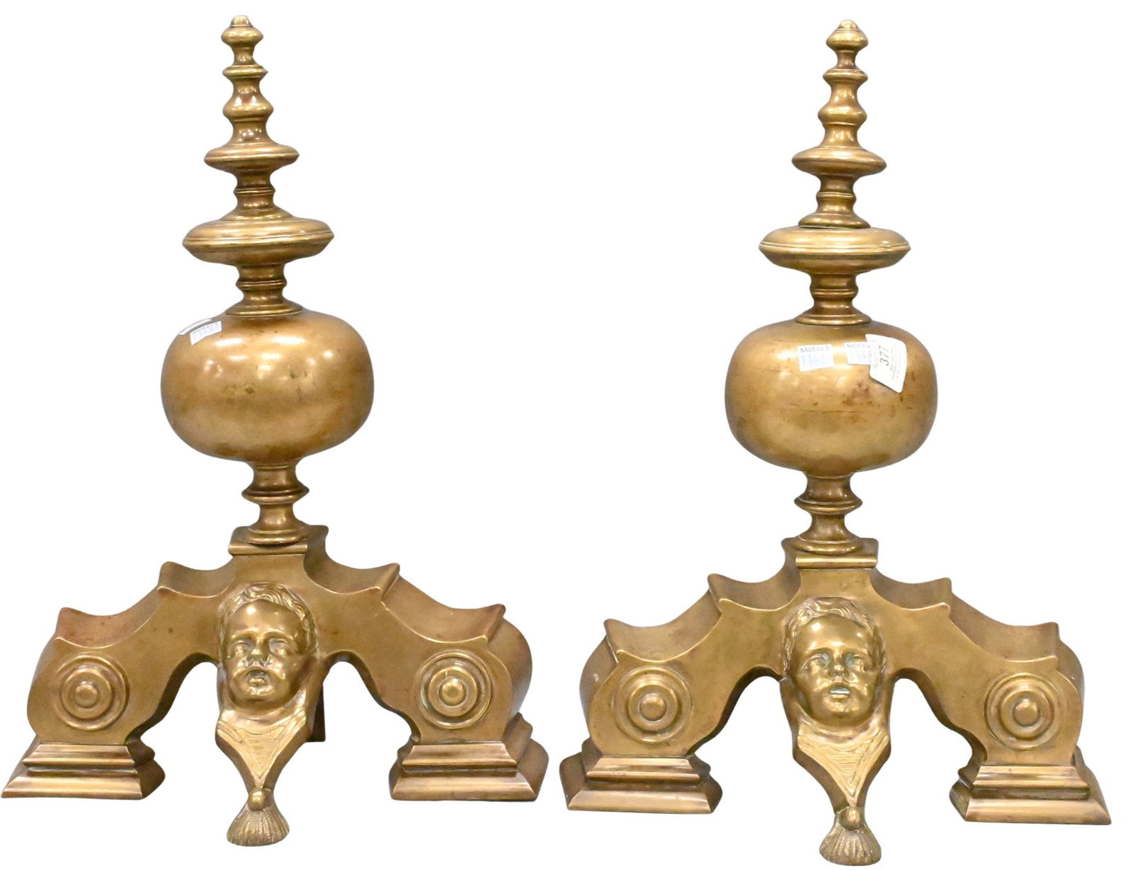 Pair of Brass Figural Andirons: Pair of Brass Figural Andirons Having urn form finials above architectural supports centered by cherub masks, raised on stepped plinth bases height 19 inches