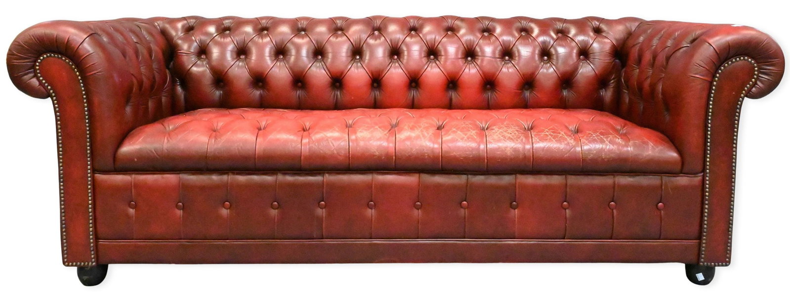 Chesterfield Maroon Leather Sofa: Chesterfield Maroon Leather Sofa having a fully button-tufted back, arms, and seat, rolled arms with nailhead trim, and leather upholstered base length 80 inches, height 29 inches Provenance: From a