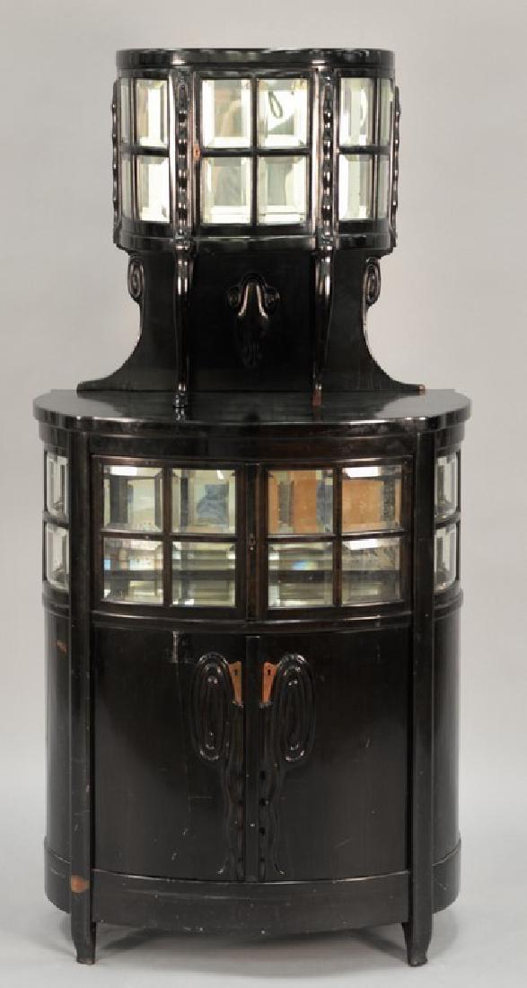 In the manner of Josef Olbrich ebonized wood and glass: In the manner of Josef Olbrich ebonized wood and glass cabinet, center and top compartment with mirrored back, circa 1910. (three bottom panels with cracks) ht. 63 3/4in., wd.29 3/4in., dp. 15 1/2in.