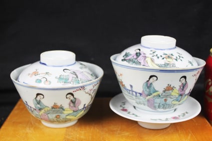 Two porcelain Famile rose lidded cups and saucers with saucer decorated with branches, peaches and