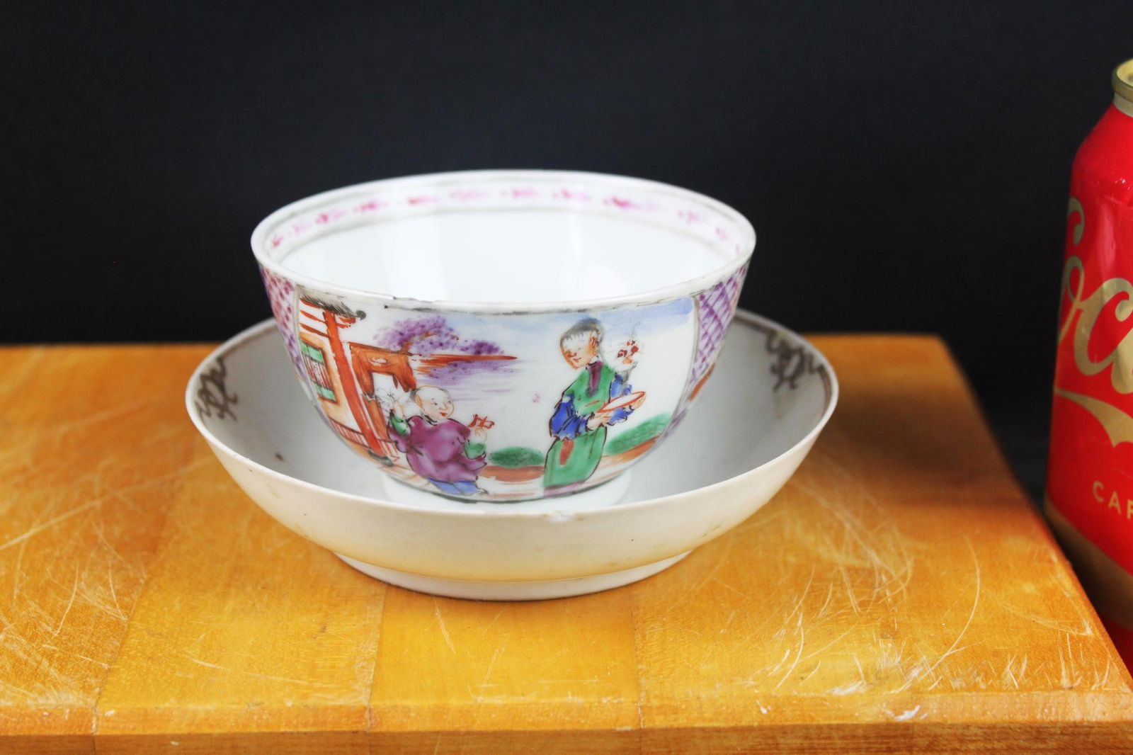 Chinese Famille Rose Porcelain Tea Bowl, Hand-Painted Figures: 3.5''x2'' A charming Chinese famille rose porcelain tea bowl, hand-painted in bright enamels with a courtyard scene featuring two figures, one holding a flower while the other stands near a pavilion.