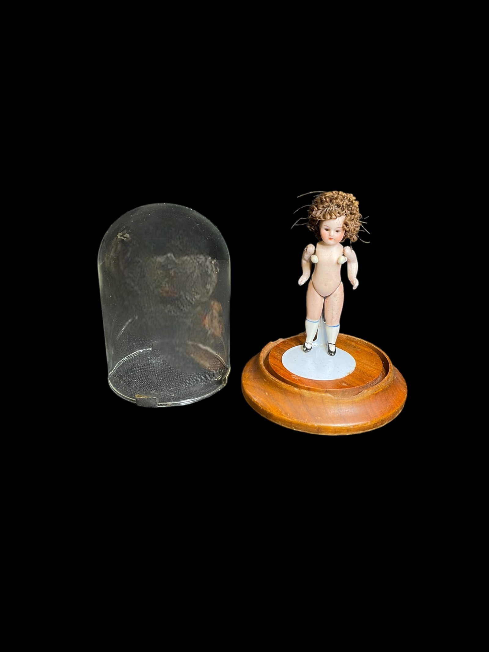 Antique Mignonette German Porcelain Doll: Antique Mignonette German Porcelain Doll. Measures 4" tall and is marked but is very hard to read. Cloche dome & stand are included and dome measures 5" tall and has 2 chips on wooden base. Hair is no