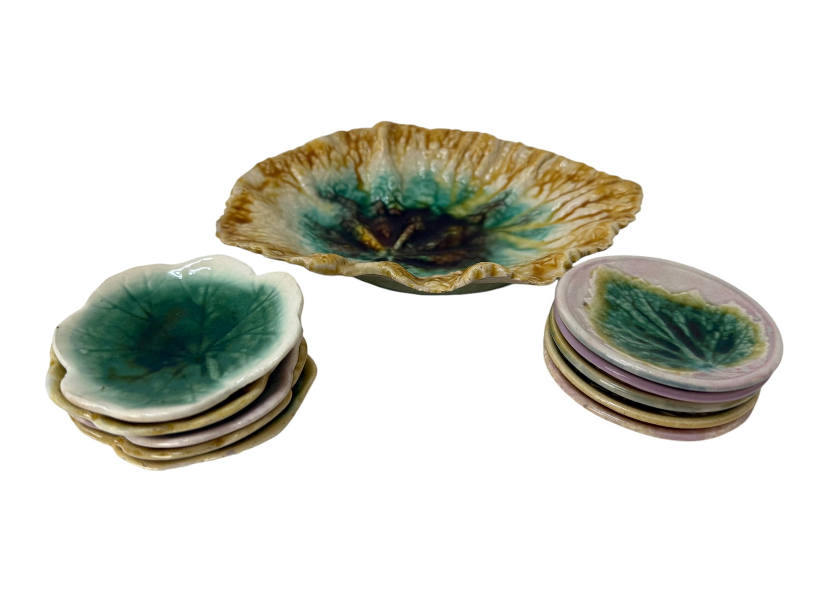 Group of 11 Majolica Pieces: Group of 11 Majolica Pieces. 10 Antique Majolica Butter Pats measure 3" diameter. 1 Antique "Dwarf Elephant Ear" Majolica Plate measures 8" x 6".