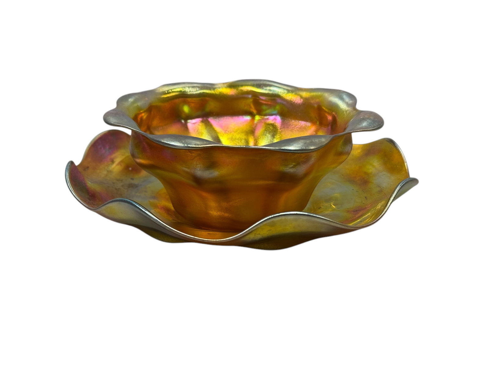 Signed L.C. Tiffany Favrile Iridescent Bowl w/ Underplate: Signed L.C. Tiffany Favril Iridescent Bowl w/ Underplate. Both pieces signed L.C.T. on the bottom and bowl has original sticker. Bowl measures 2" H x 5" W x 5" D. Underplate measures 6.25" W x 6.25" D
