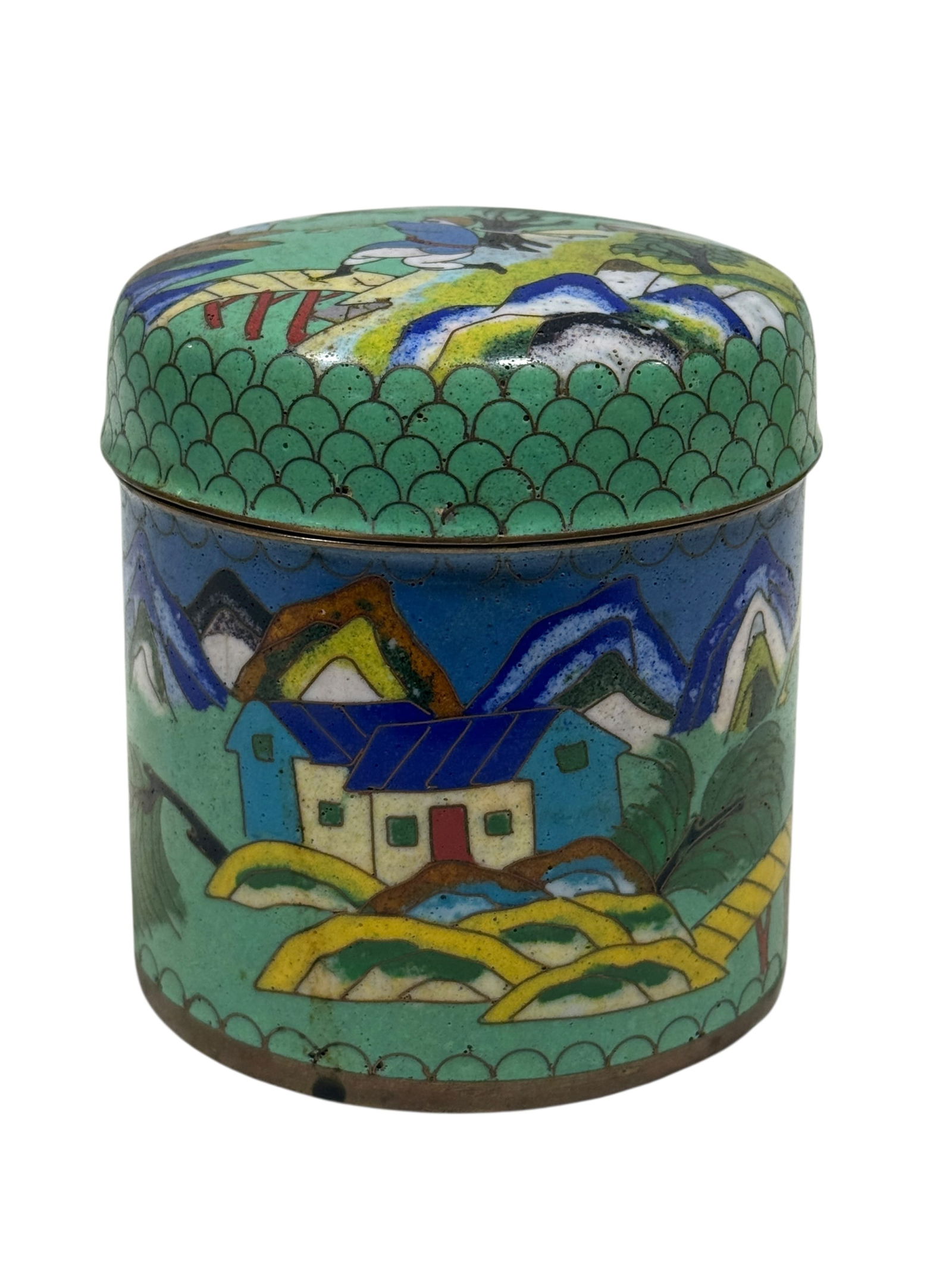1900s Chinese Cloisonne Tea Jar w/ Lid: 1900s Chinese Cloisonne Tea Jar w/ Lid. Depicting housing on lard with farmers and mountain scene on a green background. Measures 3.5" H x 3" W x 3" D. Showing wear from age.