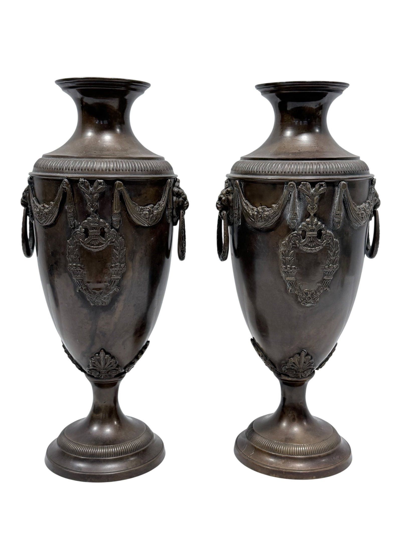 Pair of Bronze Gothic Neoclassical Lionhead Urns: Pair of Bronze Gothic Neoclassical Lionhead Urns. Features lionhead handles, laurel wreaths and other classical motifs. Has natural patina. Measures 13.5" H x 6" W x 5.25" D. Has some scratches.