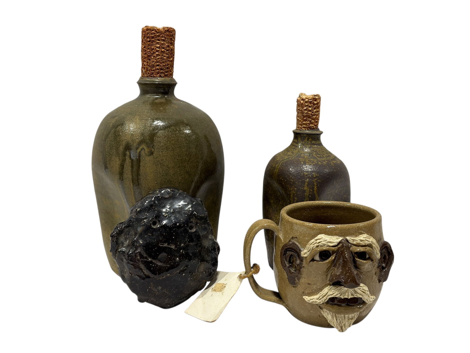 Group of 4 Pottery Pieces: Group of 4 Pottery Pieces. 2 Pottery Jugs w/ Corn Cob Stopper signed by Jason Luck & Sid Luck measure 7" Tall & 9.75" Tall. North Cole Pottery Face Mug is signed, has tag and measures 3.5" H x 4.5" W.