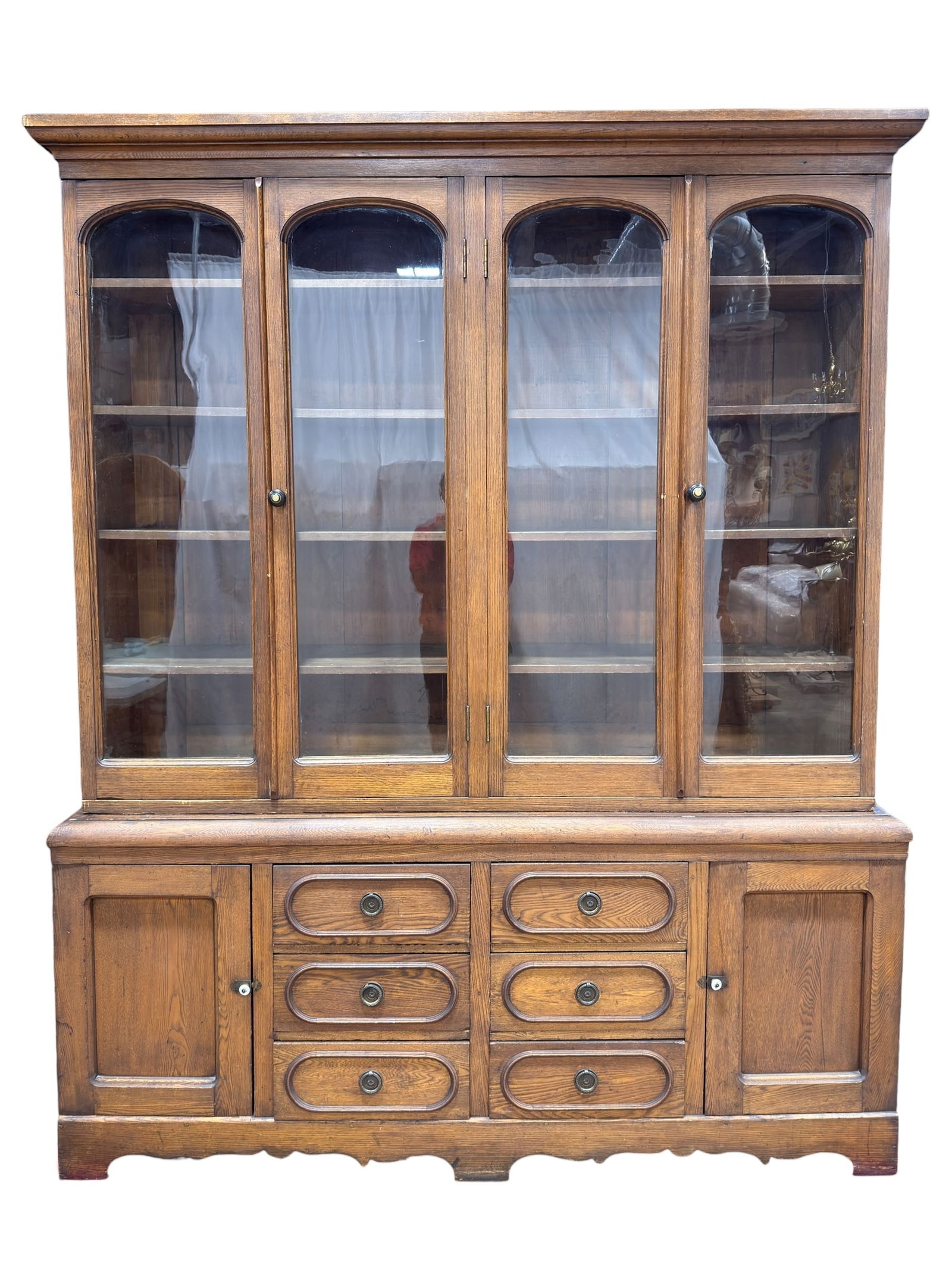 19th C. English Oak & Chestnut Glazed Bookcase Cabinet: A substantial 19th C. (Circa mid 1800s) two-part bookcase cabinet, likely English in origin, crafted in oak with secondary chestnut construction. The upper section features four glazed doors with arch