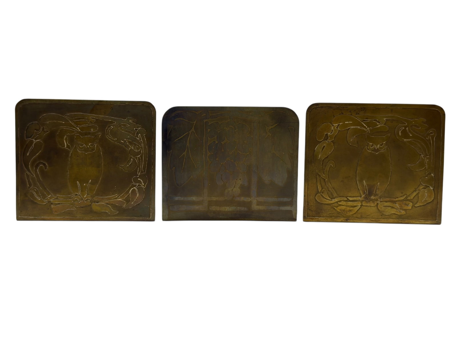 (3) Early 20th C. Arts & Crafts Brass Bookends: A decorative group of three Arts & Crafts period brass bookends, early 20th century, including a matching pair featuring stylized owls framed by flowing organic foliate forms, and a single companion b