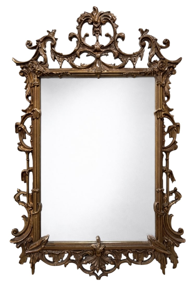 Composite Framed Ornate Mirror: Rectangular mirror set within an ornate composite frame featuring high-relief scrolling acanthus, floral elements, and a pierced rococo-style crest. Finished in a warm gilt-toned surface, the frame ha