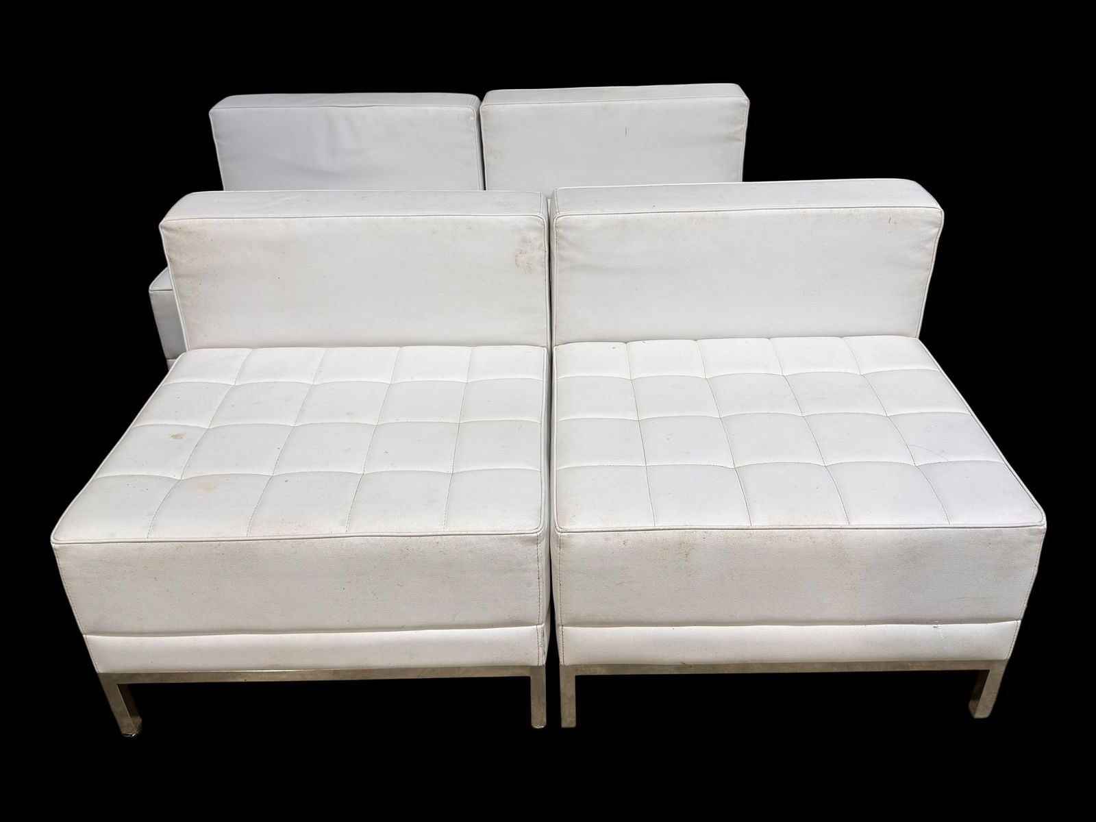 Set of 4 Contemporary White Upholstered Modular Lounge Chairs: A matching set of four contemporary modular lounge chairs upholstered in white faux leather, each featuring clean modern lines, square tufted seat cushions, and low-profile backs supported by sleek me