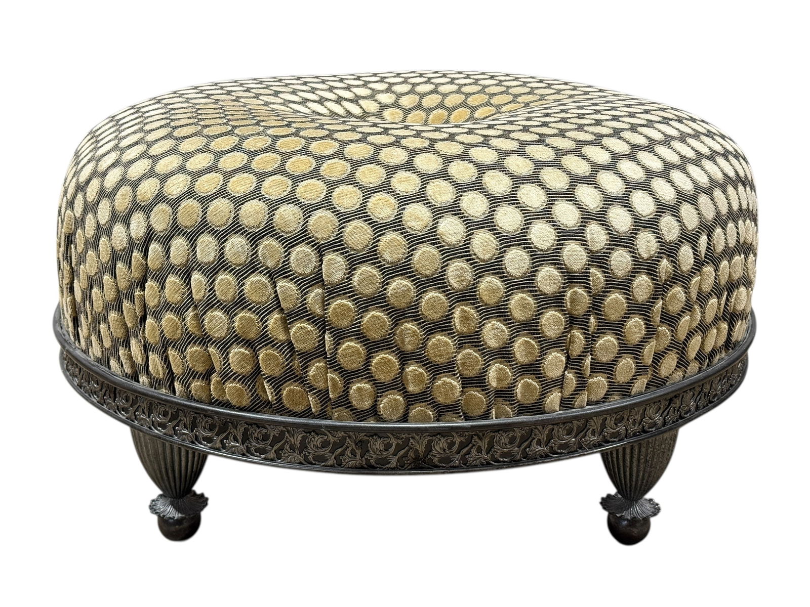 Upholstered Round Ottoman with Ornate Metal Base: This upholstered round ottoman features a generously cushioned dome form covered in a textured black ground fabric with raised ivory and pale gold dot patterning, centered by a decorative metal tufted