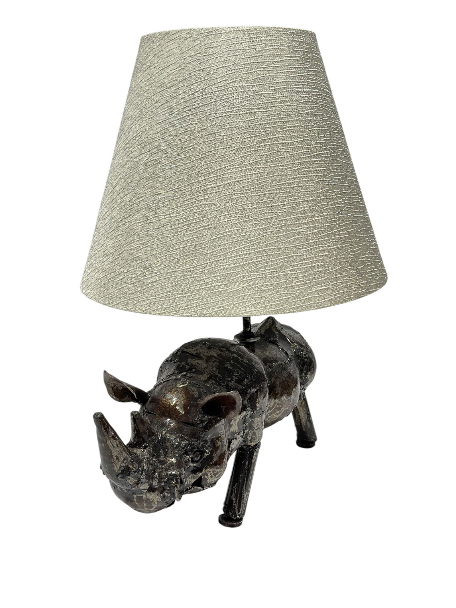 Metal Rhino Table Lamp: Whimsical and eye-catching metal rhinoceros table lamp featuring a sculptural rhino-form base with a dark, heavily textured surface finish showing intentional roughness, pitting, and mottled wear that