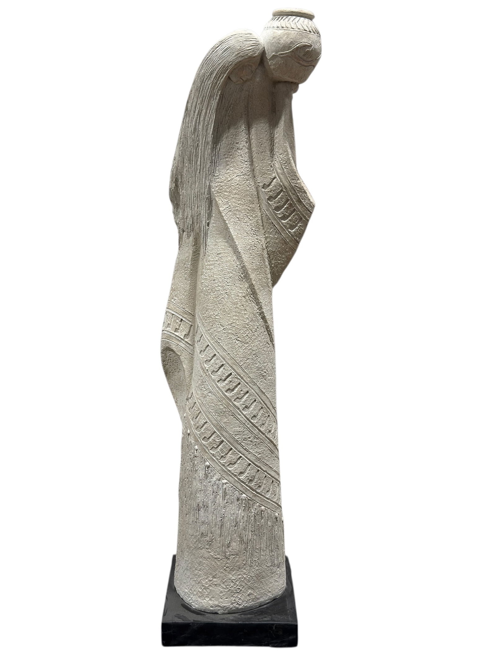 Carved Stone-Style Figurative Sculpture: This tall carved stone-style figurative sculpture depicts a stylized female form with elongated proportions, flowing hair, and a vessel balanced at the shoulder, executed in a textured pale stone or c