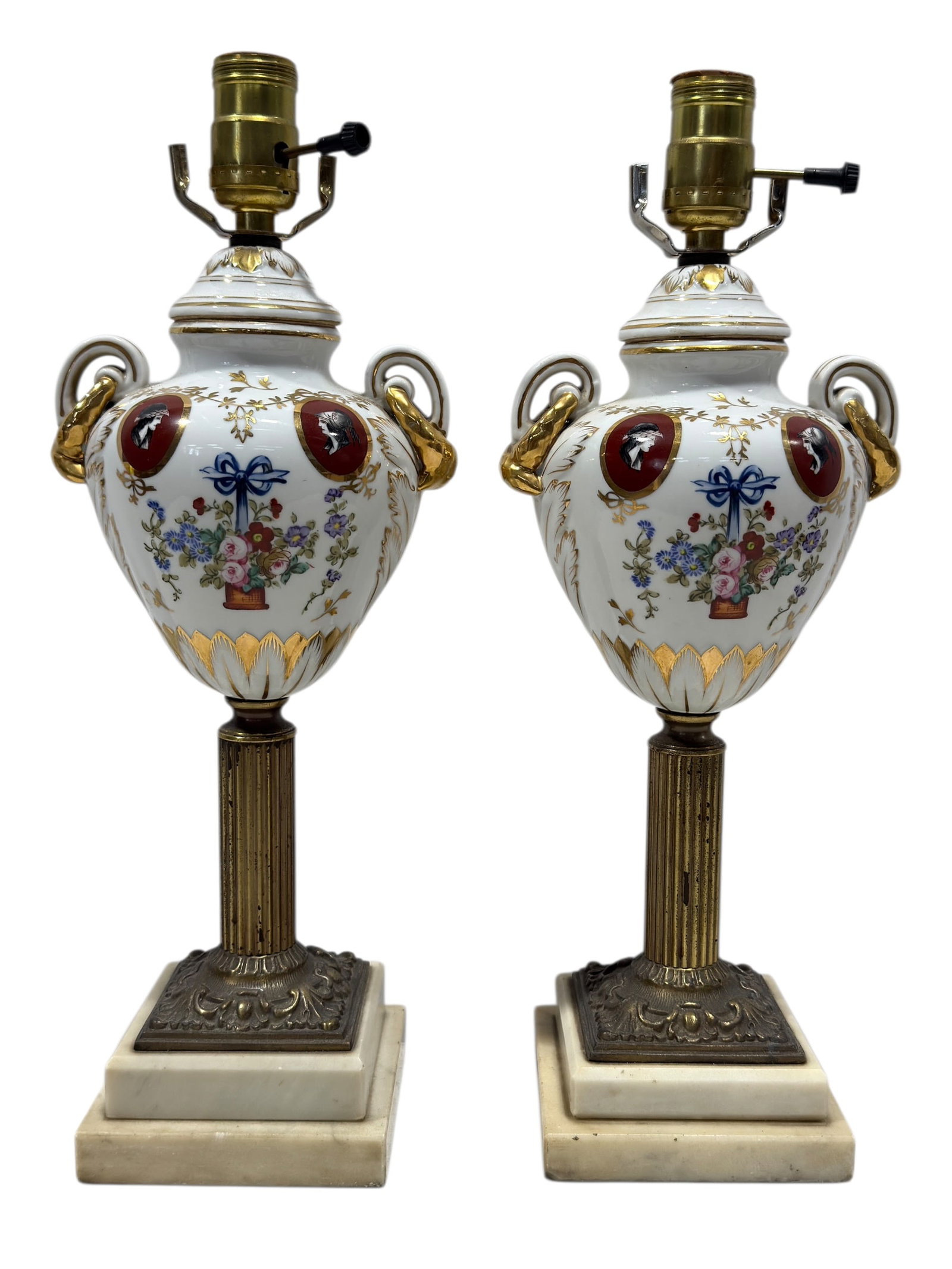 Pair of Porcelain Urn Table Lamps on Marble Bases: Pair of porcelain urn-form table lamps featuring white porcelain bodies richly decorated with hand-painted floral bouquets, gilt foliate ornament, and red oval portrait medallions depicting classical