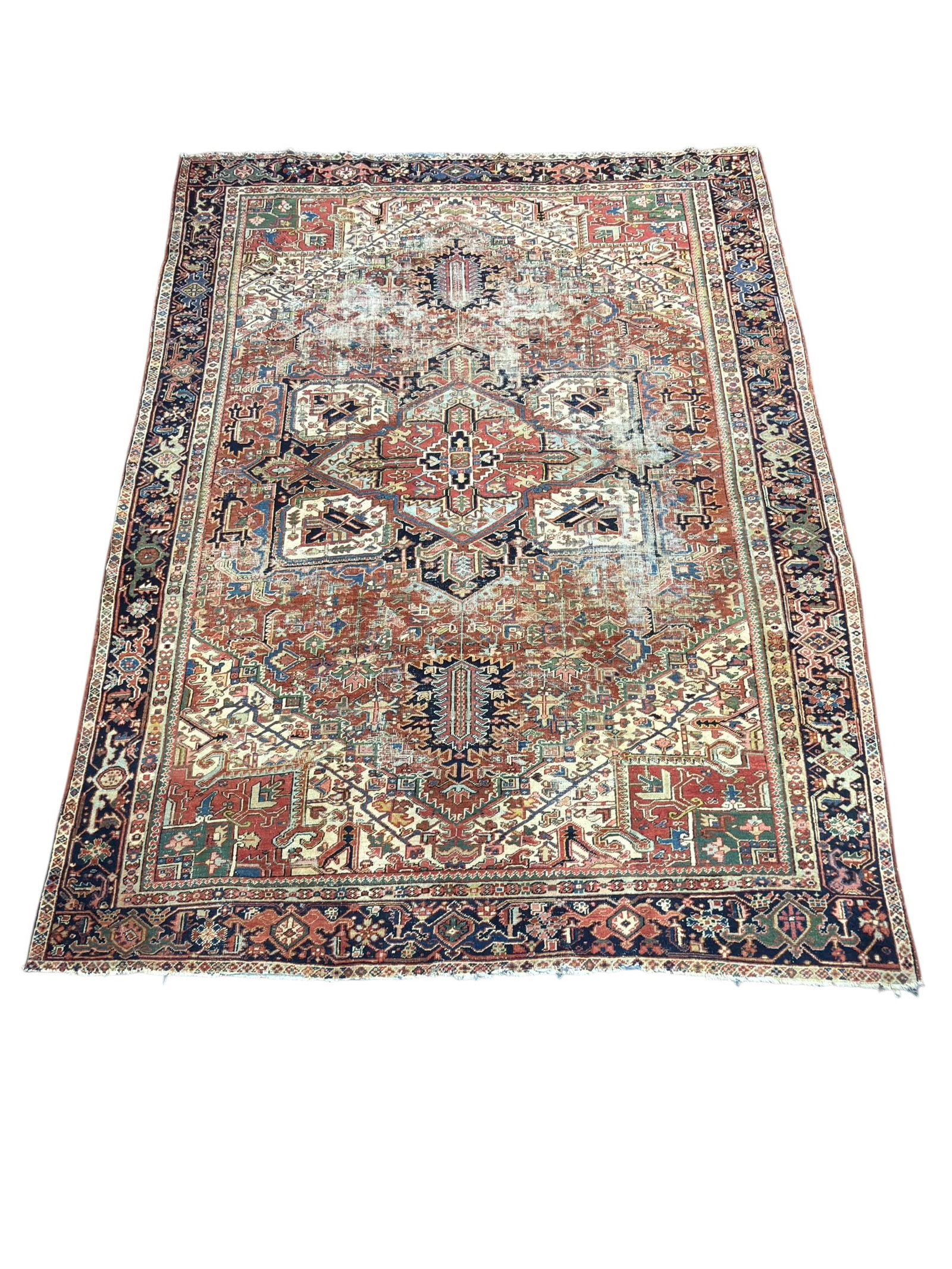 Antique Persian Heriz Hand-Knotted Wool Rug: Antique Persian Heriz hand-knotted wool rug featuring a bold geometric medallion design typical of Northwest Persian weaving, the large central stepped medallion surrounded by angular floral and triba