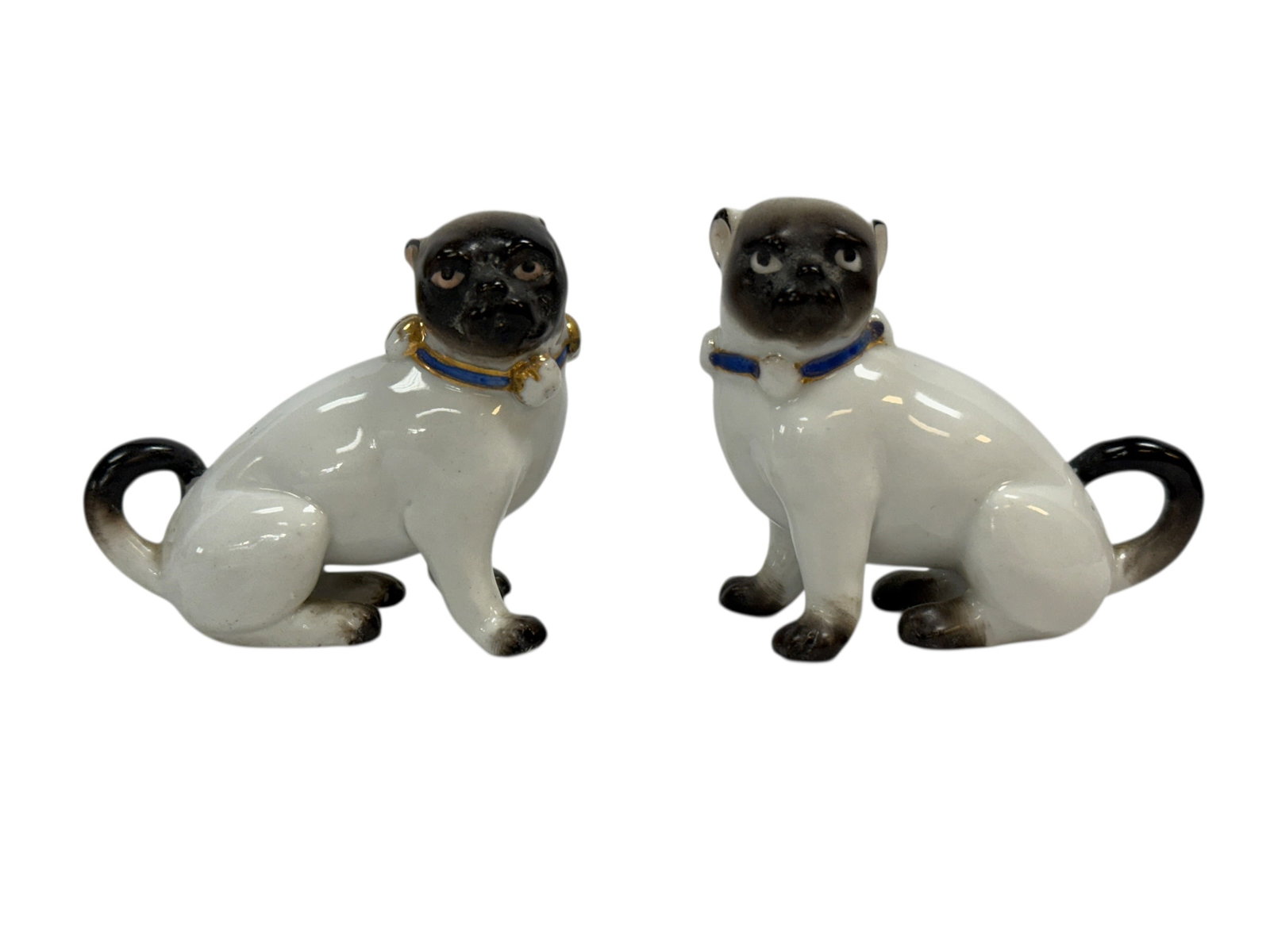 19th C. Porcelain Seated Pug Dog Figures, Pair: A charming pair of 19th century porcelain pug dog figures, each modeled seated with alert, expressive faces and tightly curled tails, decorated in a glossy white glaze with contrasting dark muzzles, e