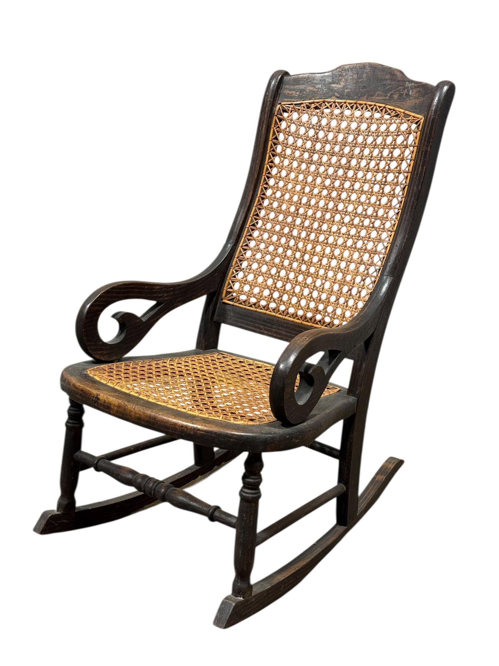 Antique Child's Cane Seat & Back Wooden Rocking Chair: A charming antique child’s rocking chair featuring a solid wood frame with gracefully shaped scrolled arms and a shaped crest rail, fitted with woven cane panels to both the seat and back, the desig