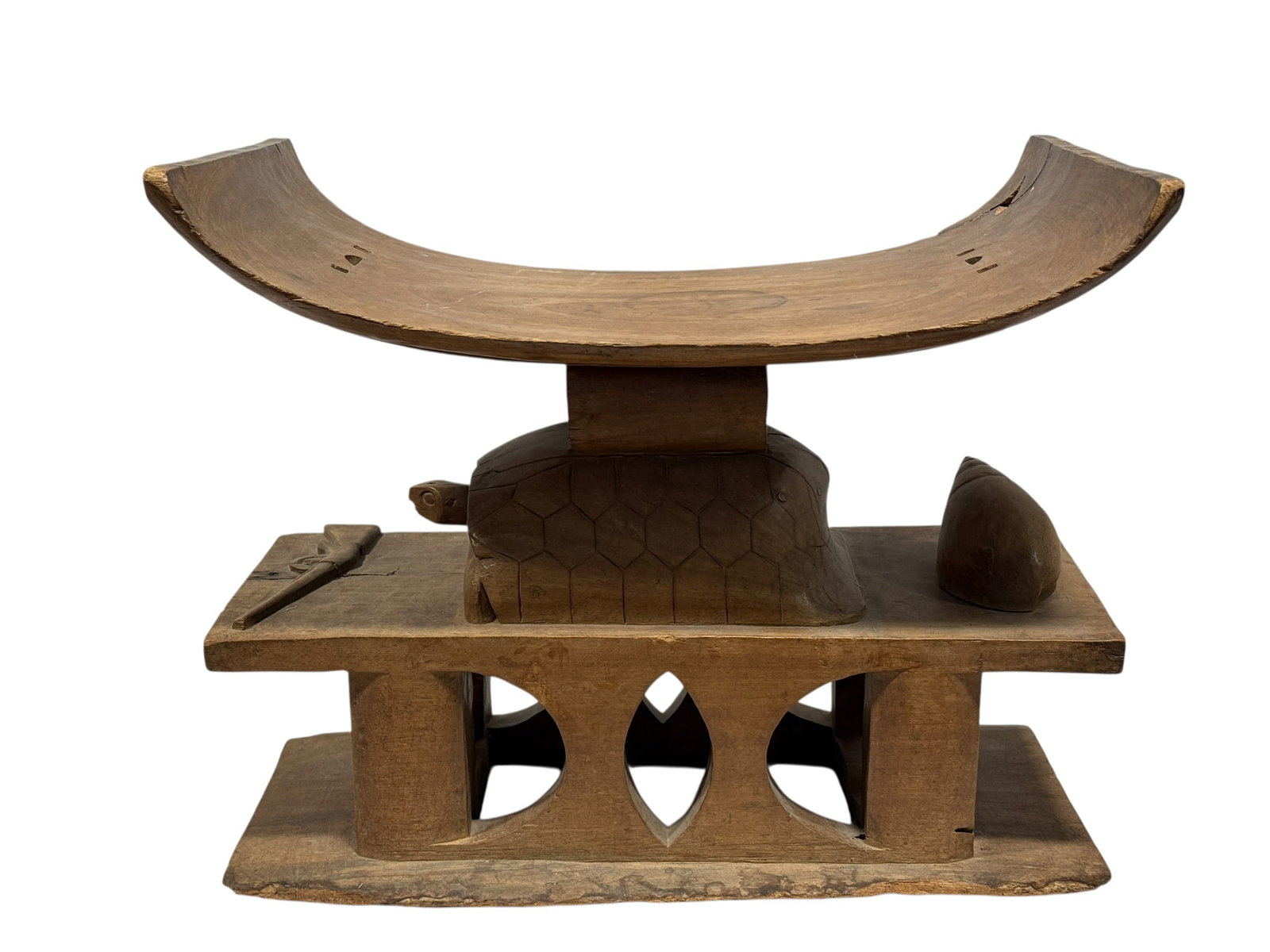 20th Century Fante / Asante Carved Wood Stool: Impressive 20th century Ghanaian carved wood stool attributed to the Fante / Asante tradition, featuring a dramatic crescent-shaped curved seat raised above a boldly sculpted central support in the fo