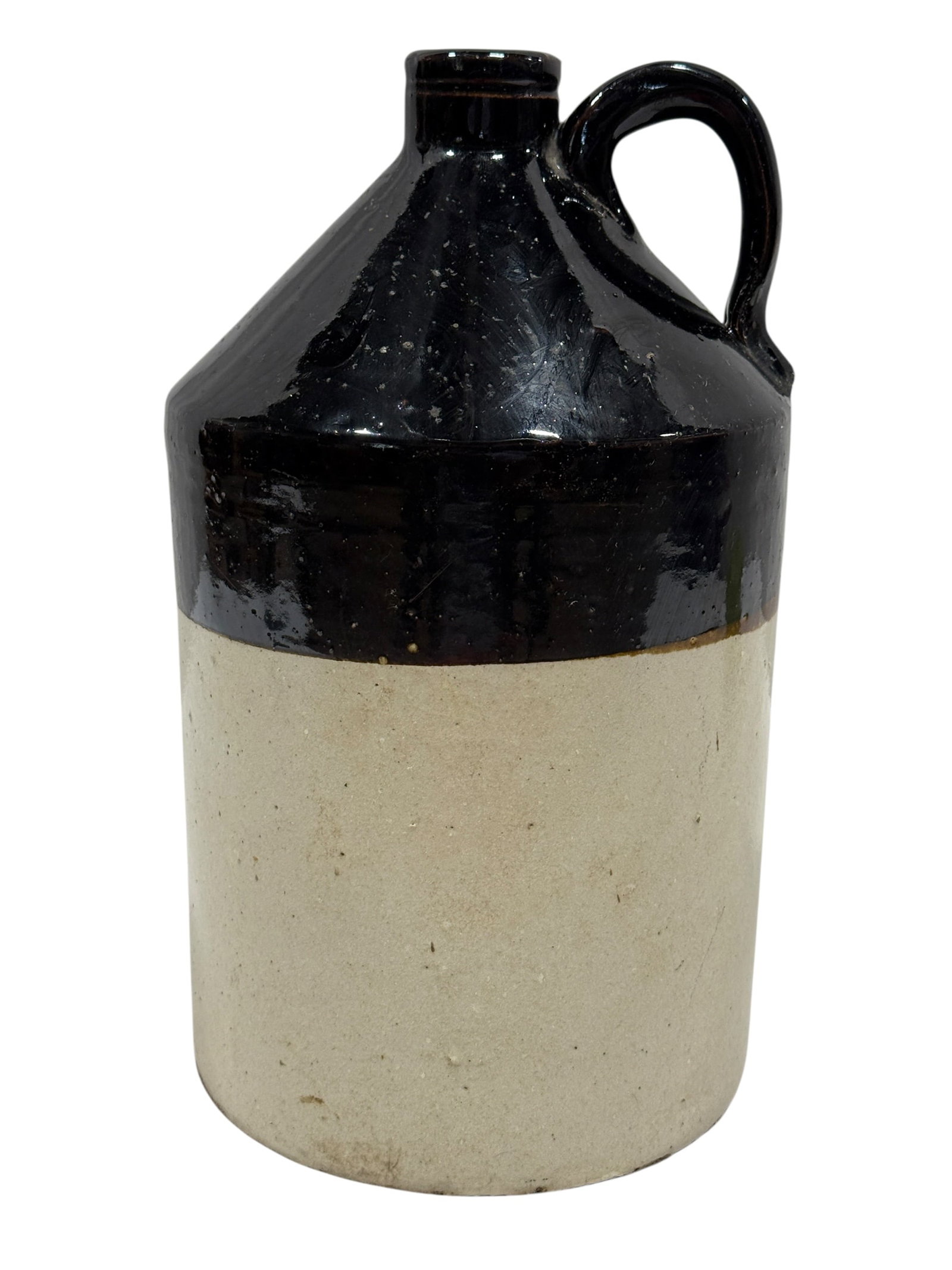 Two-Tone Albany Slip Glazed Stoneware Jug: A classic American stoneware jug featuring a sharply defined two-tone glaze, with a natural buff clay lower body and a rich, glossy Albany slip glaze covering the shoulder, neck, and applied handle, t