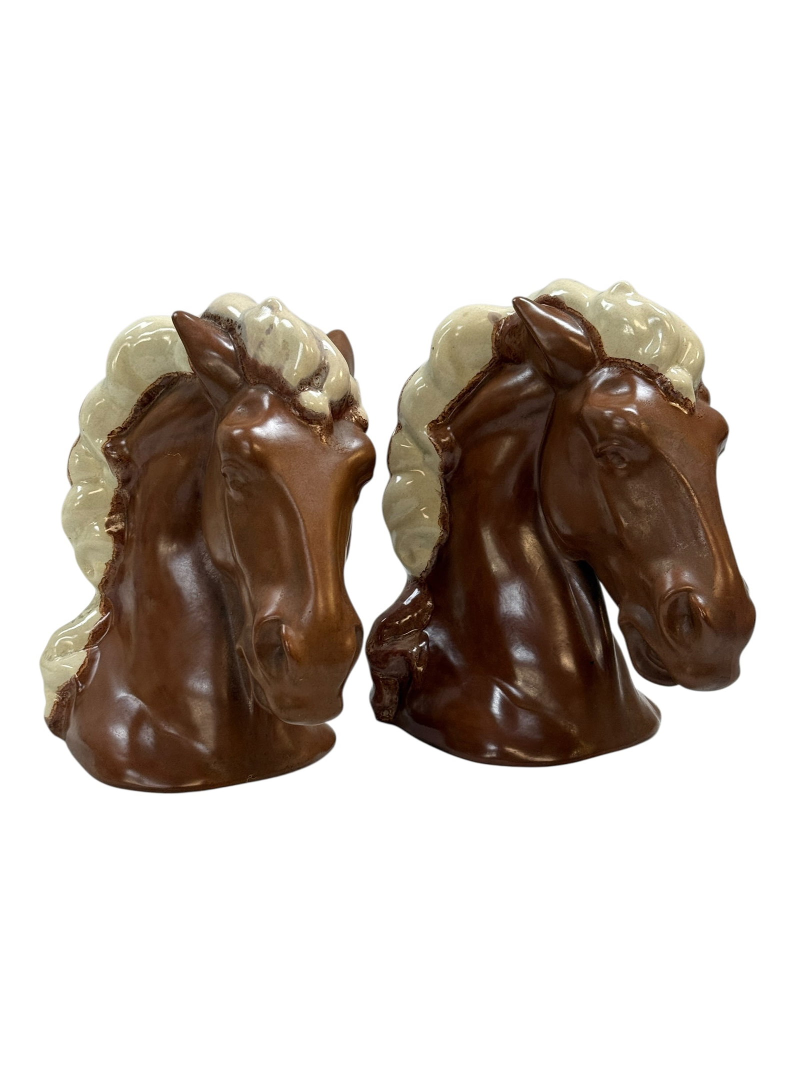 Pair of Signed Glazed Ceramic Horse Head Bookends: This pair of vintage ceramic bookends features stylized horse head sculptures with a rich brown glaze, accented by contrasting cream-colored manes. Designed with a flat, upright back for supporting bo