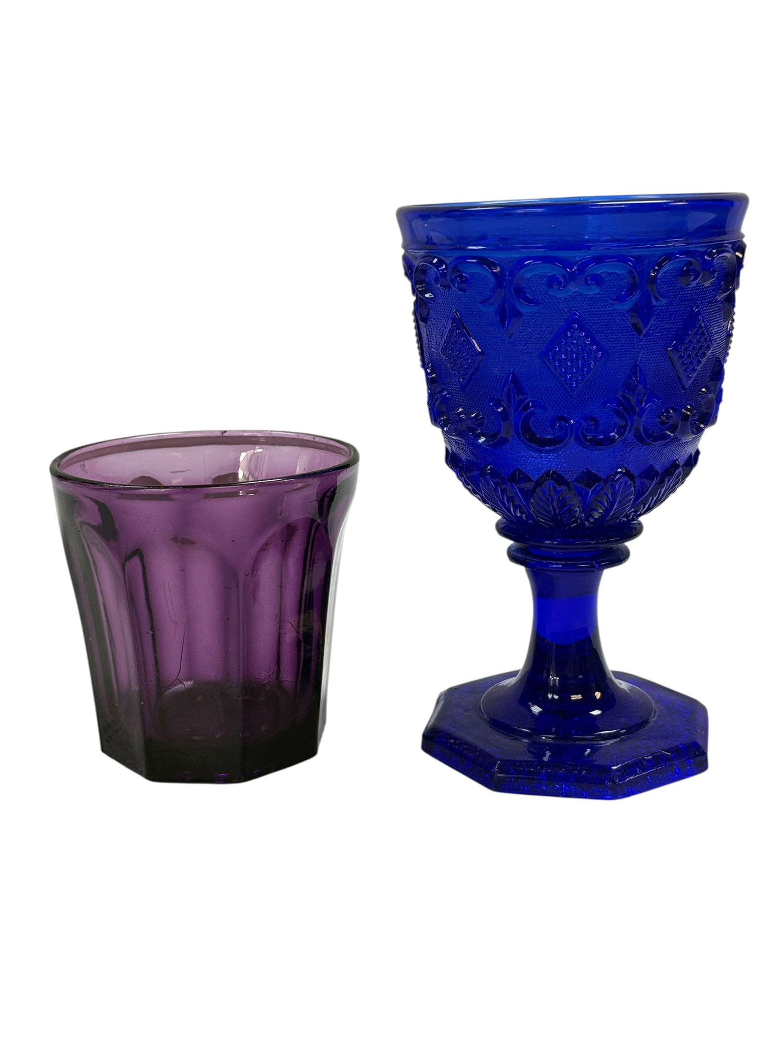 Cobalt Blue "Boston" Goblet and Purple "American Sandwich" Tumbler: This lot consists of two classic pieces of vintage American pressed glass. The Cobalt Blue "Boston" goblet is a vibrant stemmed piece featuring a detailed diamond-and-leaf embossed pattern that remain
