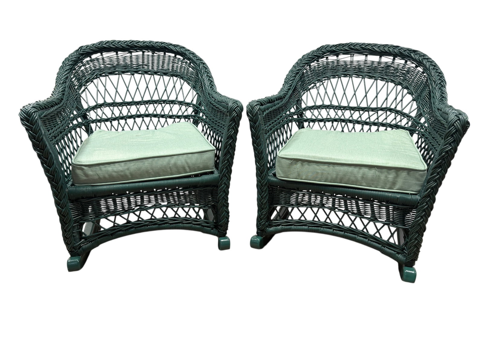 Pair of Green Resin Wicker Rocking Chairs with Cushions: Pair of woven resin wicker rocking chairs featuring rounded barrel-form backs with an open lattice weave, braided armrests, and a painted dark green finish. Each chair is fitted with a matching loose 