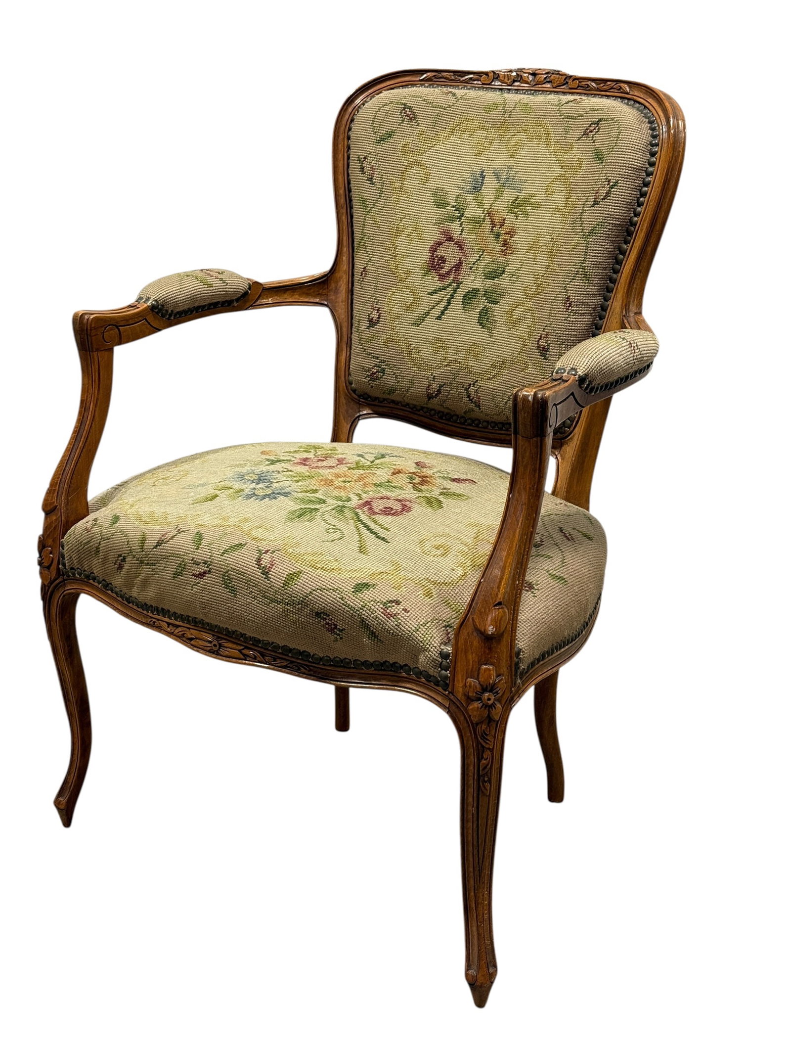 Louis XV Style Walnut Needlepoint Upholstered Armchair: Elegant Louis XV-style walnut armchair featuring a molded serpentine crest rail with carved floral motif, shaped padded back, scrolling open arms, carved supports, serpentine seat rail, and graceful c