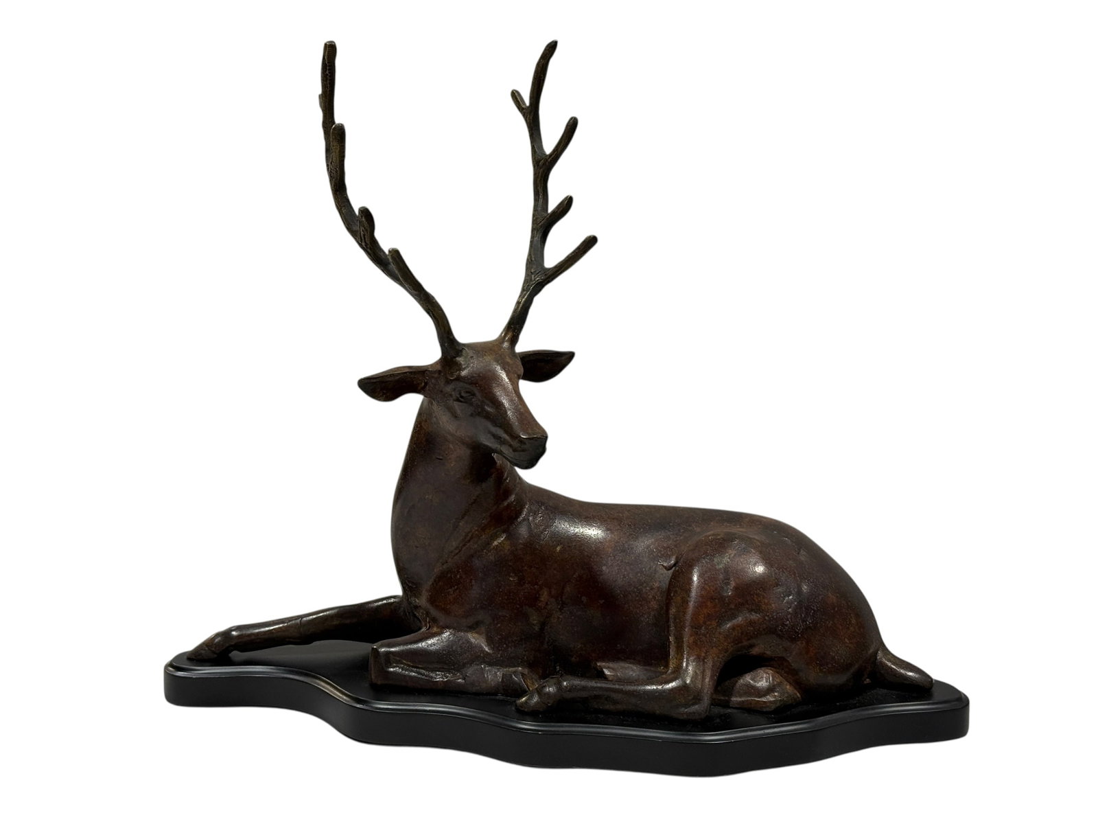 Patinated Metal Reclining Stag Sculpture: A cast metal sculpture depicting a reclining stag or deer with large antlers. The figure is modeled in a resting position with its legs tucked beneath its body and its head turned slightly to the