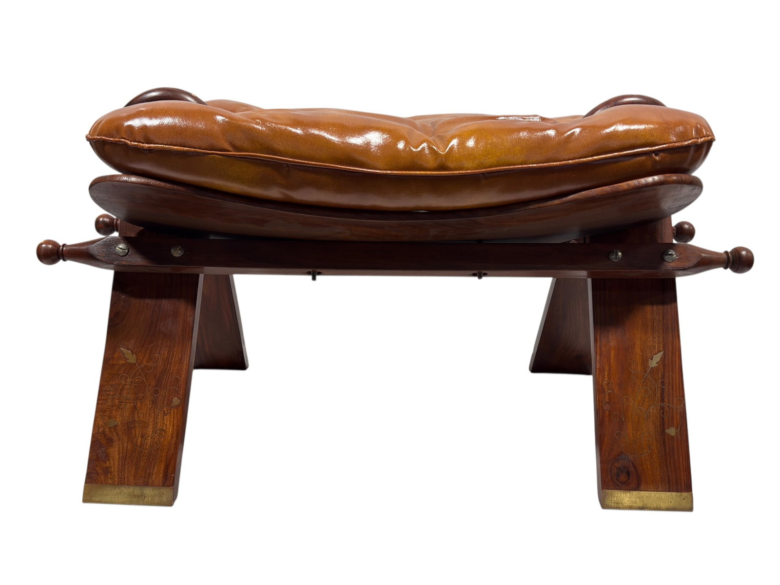 Anglo Indian Brass Inlaid Rosewood Camel Saddle Stool: A distinctive Anglo-Indian camel saddle stool crafted in richly toned rosewood, featuring a broad rectangular seat fitted with a deeply button-tufted caramel-brown leather cushion. The saddle-inspired