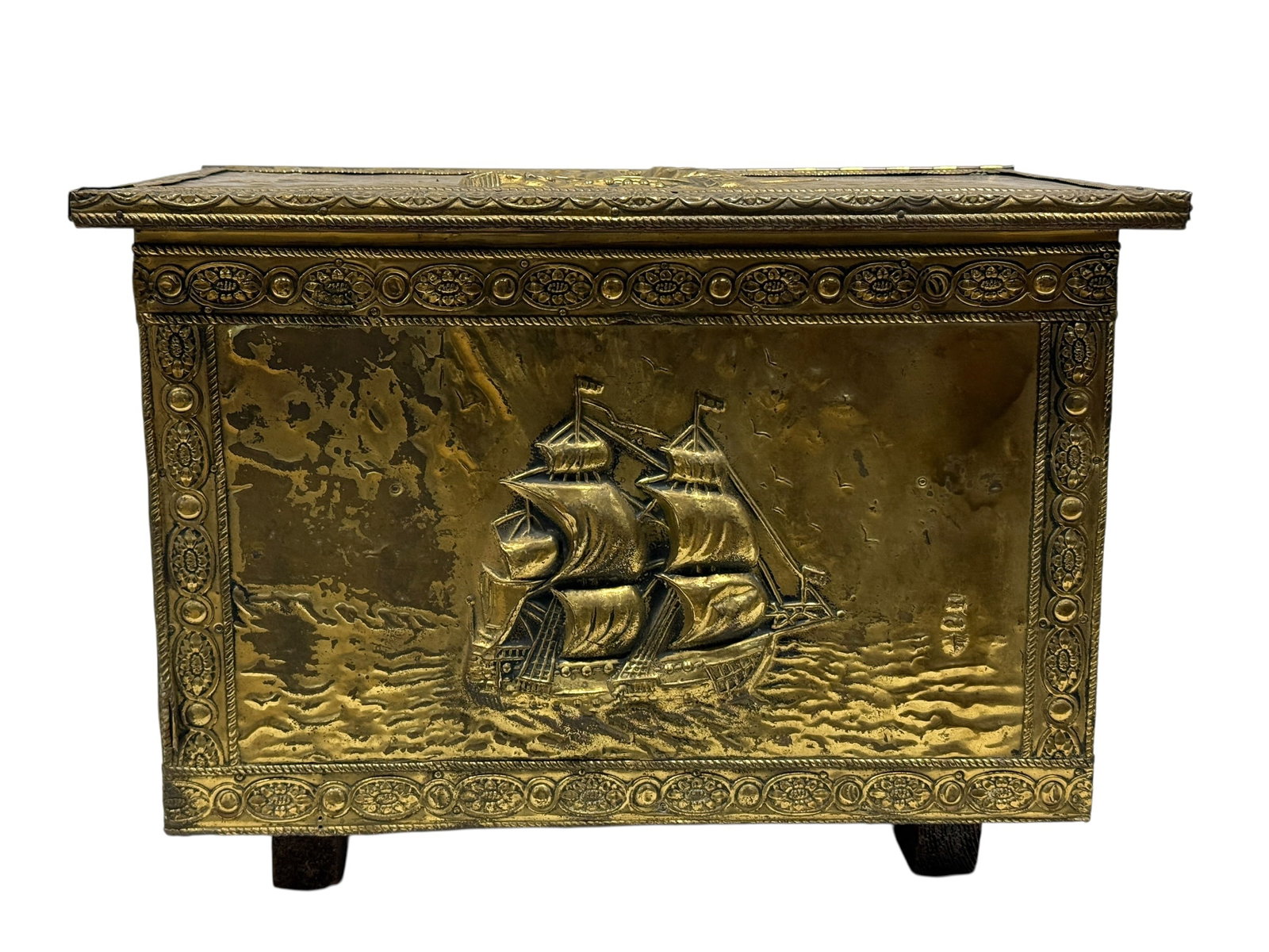 English Repousse Brass Maritime Coal Box: A decorative English fireside coal or kindling box of rectangular chest form, constructed in wood and clad with embossed brass panels depicting fully rigged sailing ships navigating textured, rolling 