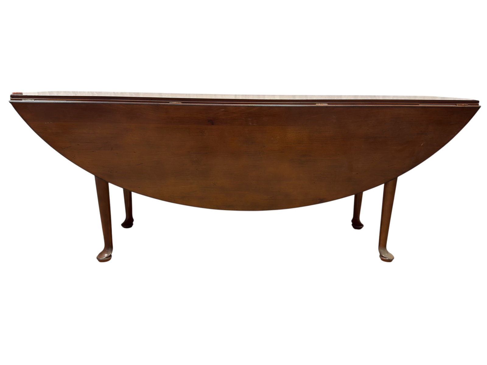 20th C. Queen Anne Style Mahogany Drop Leaf Dining Table: A handsome Queen Anne-style mahogany dining table featuring a long rectangular center section flanked by broad hinged drop leaves that create a graceful oval top when fully extended. The warm mahogany